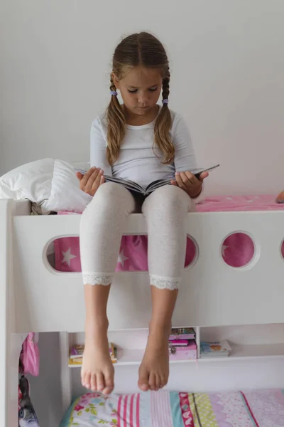 在舒适的家里在床上看书的白种女孩的正面视图 — 图库照片