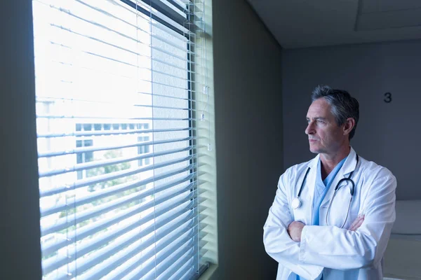 病院の窓から見る思慮深い白人男性医師の正面図 — ストック写真