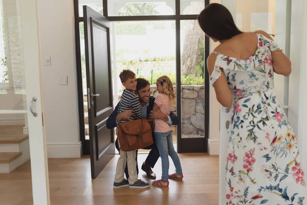 幸福的白种人父亲拥抱他的孩子们 他进入房子 而母亲看着他们前视图 — 图库照片