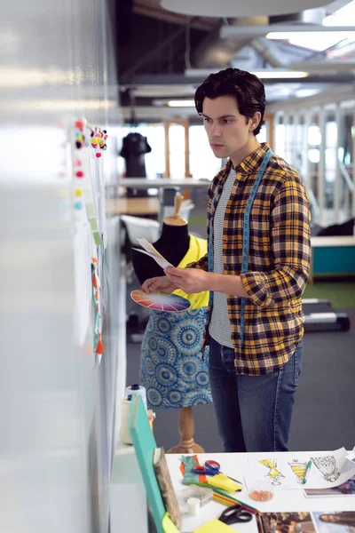オフィスでスケッチを見ている白人男性ファッションデザイナーの側面図 — ストック写真