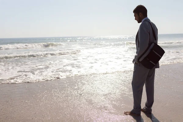 ビーチに立つ思慮深い若い混合人種ビジネスマンの背面図 — ストック写真