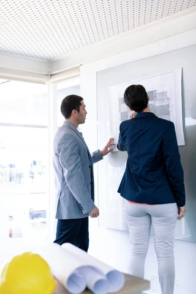 Rear View Caucasian Architects Discussing Blueprint Glass Board Modern Office — Stock Photo, Image