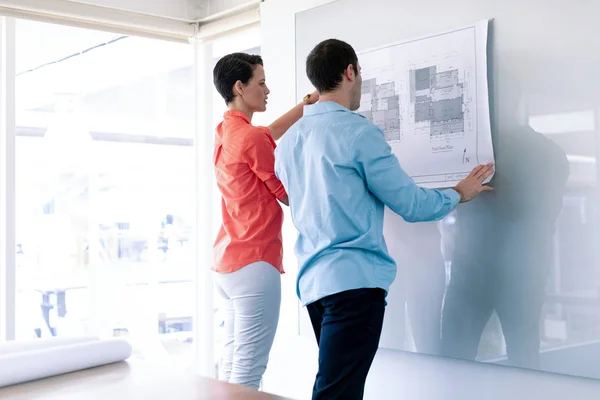 Rear View Caucasian Architects Discussing Blueprint Glass Board Modern Office — Stock Photo, Image
