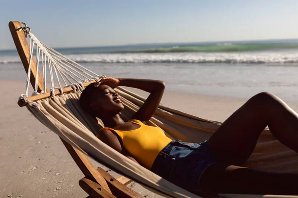 年轻的非洲裔美国妇女在海滩上的吊床上放松的侧视图 — 图库照片