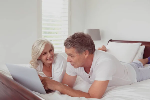 快適な家の寝室でベッドに横たわっている間 ラップトップを使用してアクティブな白人のカップルの側面図 — ストック写真