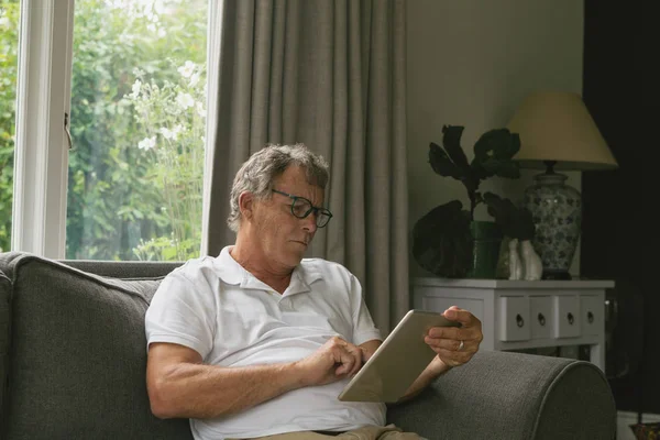 Vista Frontal Homem Caucasiano Sênior Ativo Sentado Sofá Usando Tablet — Fotografia de Stock