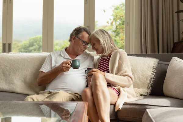 快適な家でソファでコーヒーを飲むロマンチックなアクティブな白人カップルの正面図 — ストック写真