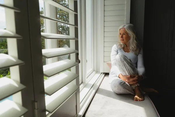 自宅の窓から見る思慮深い現役白人女性の正面図 — ストック写真