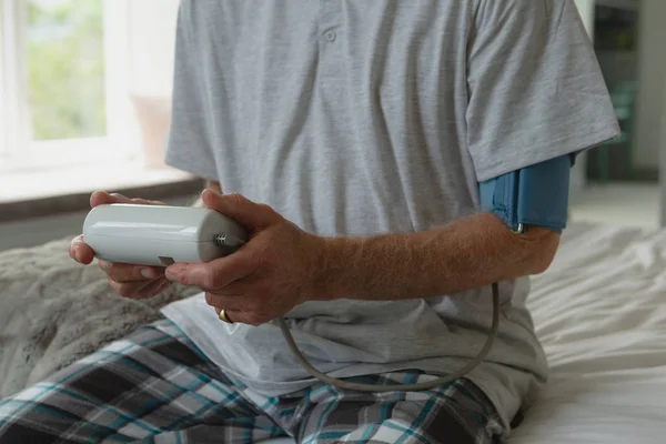 自宅の寝室で血圧を測定する男性の中間部 — ストック写真