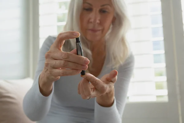 活跃高级白种妇女在家里用血糖仪测试血糖水平的正面观点 — 图库照片