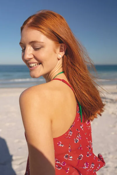 快乐的红发白种女人站在沙滩上的侧视图 — 图库照片