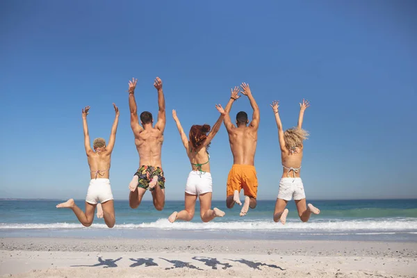 一群不同的朋友在海滩上一起跳的后视镜 — 图库照片