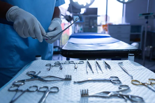 Mid section close-up of surgeon holding surgical instrument in operating room at hospital.