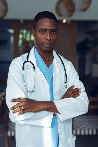 病院のロビーで腕を組んで立っているアフリカ系アメリカ人の男性医師の肖像画 — ストック写真