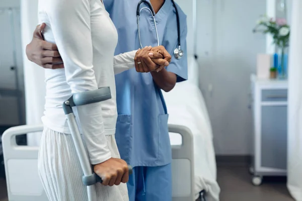 女医生中段帮助混血女病人在医院病房行走 — 图库照片
