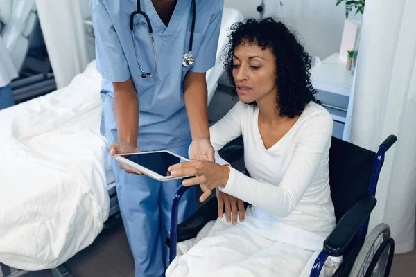 サイドビューアフリカ系アメリカ人の女性医師が 病院の病棟でデジタルタブレットを使用する障害のある女性患者を支援 — ストック写真