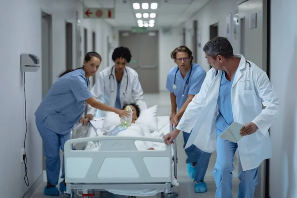 医疗多元化团队在医院走廊推紧急担架床的前视图 — 图库照片