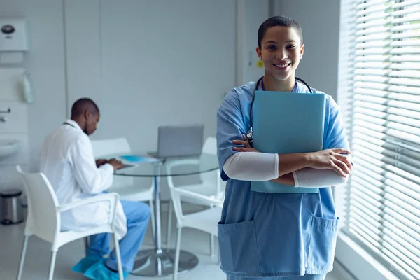 非洲裔美籍医生在医院的办公桌前工作时 女医生保持着档案 面带微笑的形象 — 图库照片