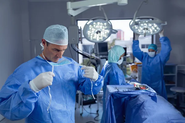 Widok Przodu Kaukaski Mężczyzna Chirurg Noszenie Maski Chirurgicznej Podczas Różnorodnych — Zdjęcie stockowe