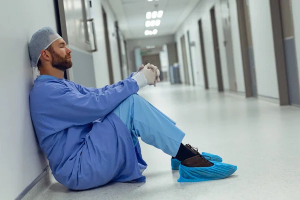 Side View Tensed Caucasian Male Surgeon Sitting Corridor Hospital — Stock Photo, Image