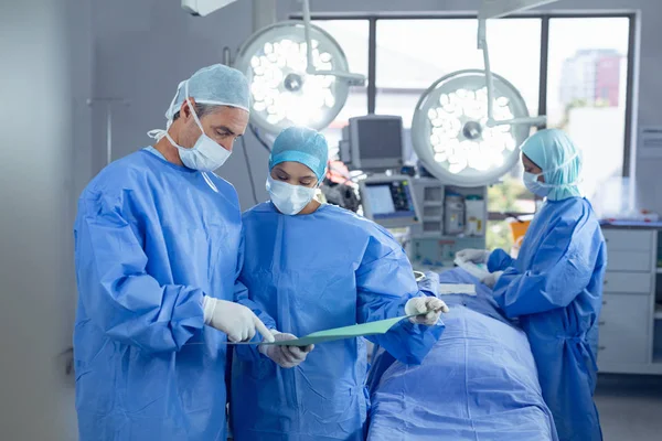 Visão Frontal Diversos Cirurgiões Discutindo Sobre Arquivo Médico Sala Operação — Fotografia de Stock