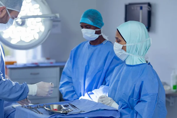 病院の手術室で手術を行う多様な外科医の側面図 — ストック写真