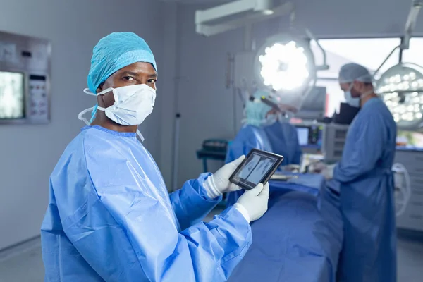 Hastanede Ameliyat Hanesinde Çalışan Çeşitli Cerrahlar Dijital Tablet Tutan Afrikalı — Stok fotoğraf