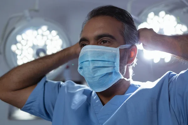 在医院手术室里 穿着外科口罩的成熟混血男外科医生的正面视角 — 图库照片
