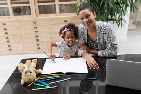 自宅のテーブルの上で彼女の宿題で彼女の娘を助けるアフリカ系アメリカ人の母親の肖像画 — ストック写真