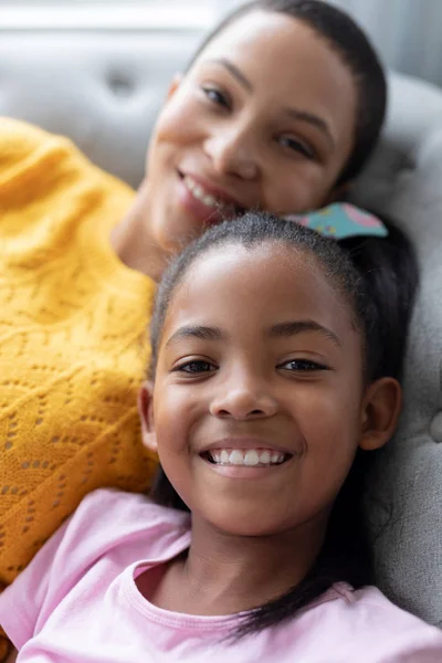 自宅のリビングルームでソファでくつろぐアフリカ系アメリカ人の母と娘の肖像画 — ストック写真