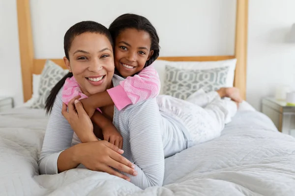 自宅の寝室で抱き合うアフリカ系アメリカ人の母と娘の正面図 — ストック写真
