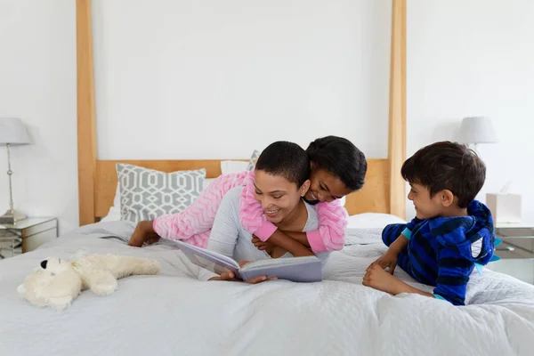 自宅の寝室で物語の本を読みながら楽しむアフリカ系アメリカ人の母と子供の正面図 — ストック写真