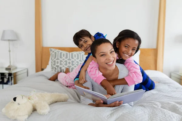 在卧室里读故事书时 非洲裔美国人母亲和孩子在享受乐趣的正面视图 — 图库照片
