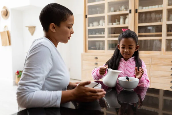 在厨房餐桌上用餐时 非洲裔美国人母女相互互动的侧视图 — 图库照片