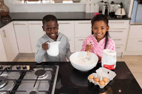 非裔美国人兄弟姐妹在厨房工作台准备食物的正面视图 — 图库照片