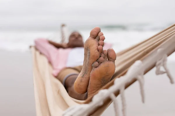 ビーチのハンモックで頭の後ろに手を置けて眠っているアフリカ系アメリカ人男性の低角図 — ストック写真