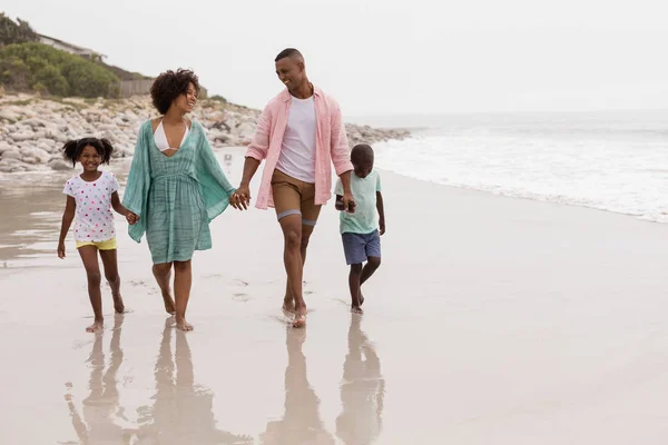 ビーチで手をつないで一緒に歩く幸せなアフリカ系アメリカ人の家族の正面図 — ストック写真