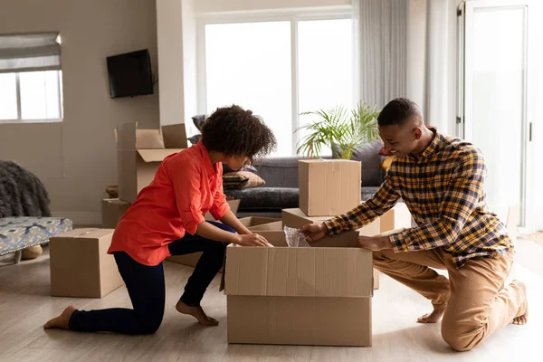 非洲裔美国人夫妇打开纸板箱在家里客厅的侧视图 — 图库照片