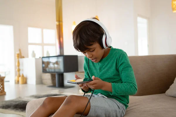 Vista Frontal Niño Americano Con Auriculares Juego Teléfono Móvil Sofá —  Fotos de Stock