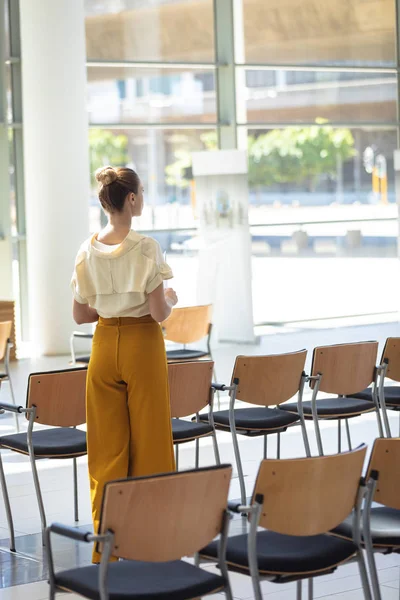 站在空的会议室里的年轻白种女性高管的后视图 — 图库照片