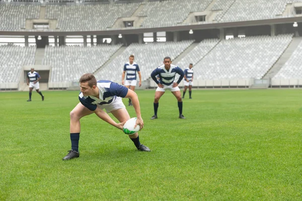 Side view of group of diverse male rugby players playing rugby match in stadium