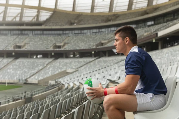 Düşünceli Beyaz Erkek Rugby Oyuncusu Stadyumda Ragbi Topuyla Oturuyor — Stok fotoğraf
