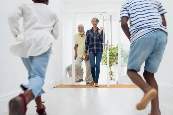 非洲裔美国人的孩子跑向他们的祖父母在家里的大厅的后视图 正宗的退休老人生活理念 — 图库照片