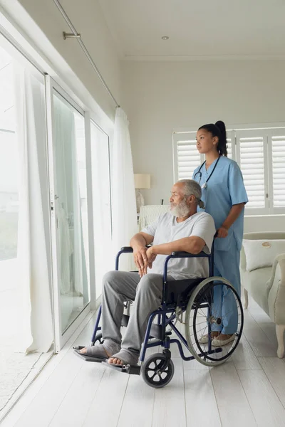 屋内車椅子の医療従事者と男性の側面図 本物のシニアリタイアライフコンセプト — ストック写真