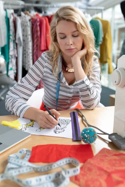 白人女性时装设计师在设计工作室桌子上画草图的前景 — 图库照片