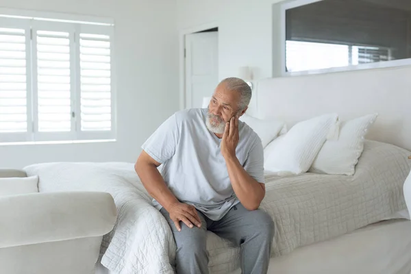 ベッドルームのベッドの上に座って思慮深いシニア白人男性の側のビュー 本物の高齢者のライフコンセプト — ストック写真