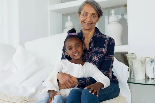 アフリカ系アメリカ人の女の子とベッドに座っている混合人種の祖母の肖像画クローズアップ 本物のシニアリタイアライフコンセプト — ストック写真