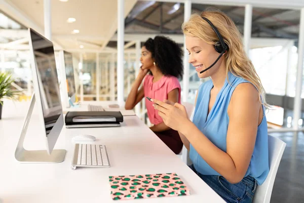 办公室使用移动电话的不同女性客户服务主管的侧视图 — 图库照片