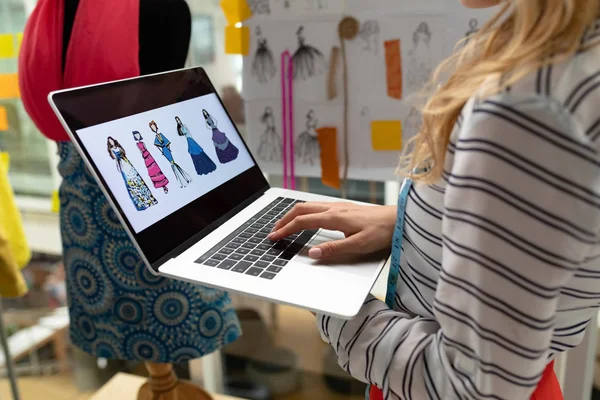白种人女性时装设计师在设计工作室使用笔记本电脑的中间部分 — 图库照片