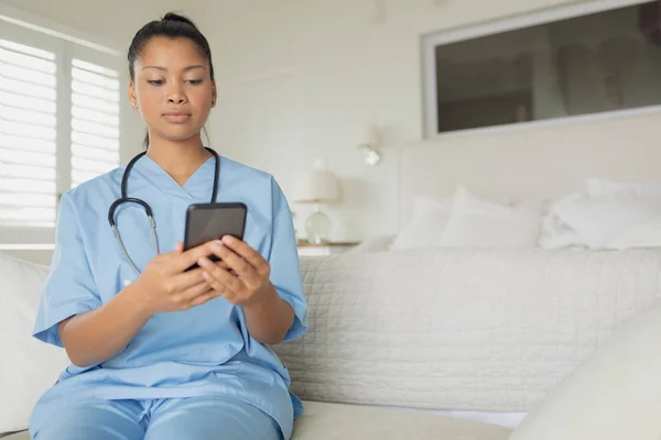 スマートフォンを屋内で使用する混合人種医療従事者の正面図 本物のシニアリタイアライフコンセプト — ストック写真
